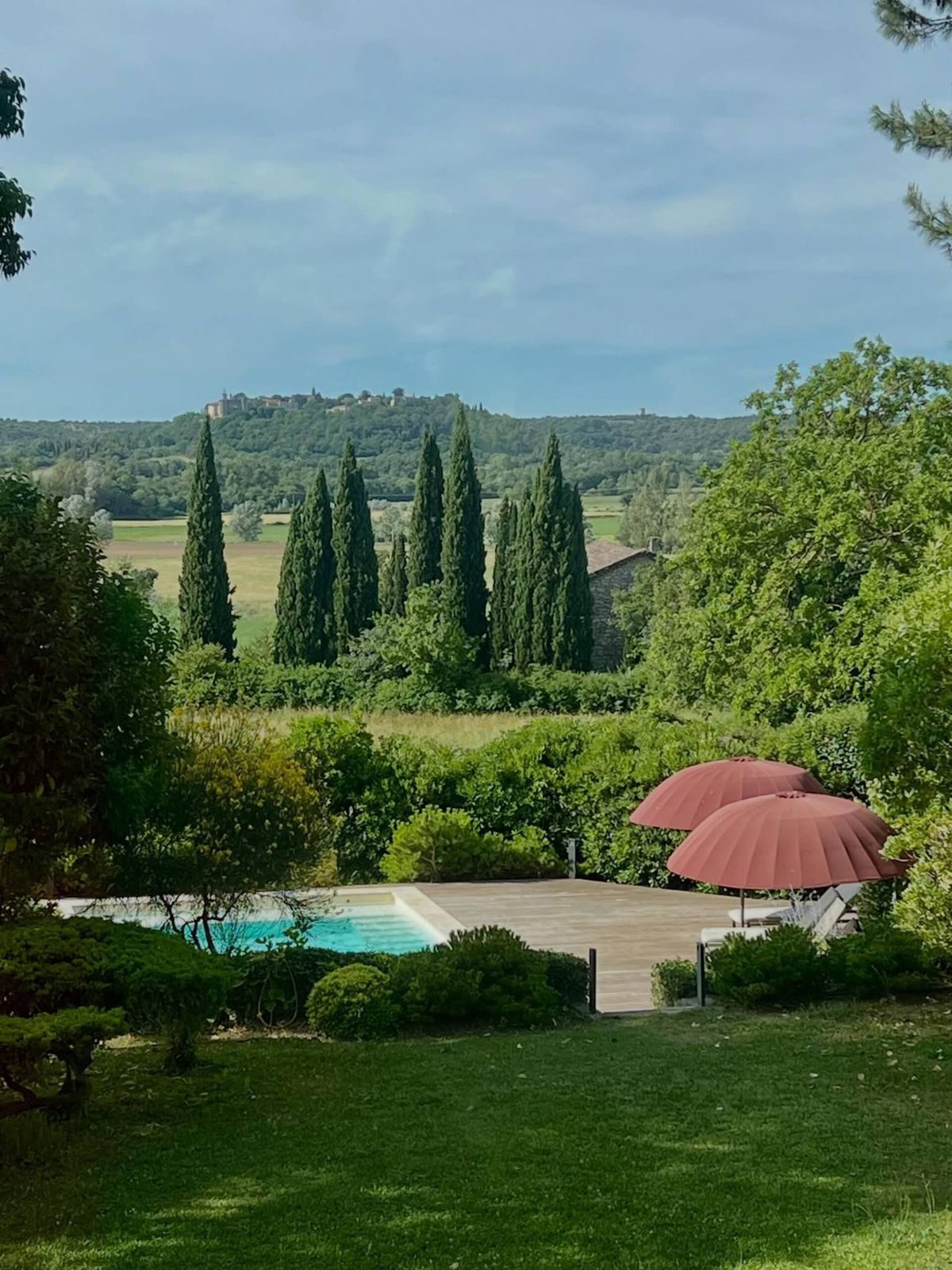 Vue sur la piscine et les parasols depuis le jardin